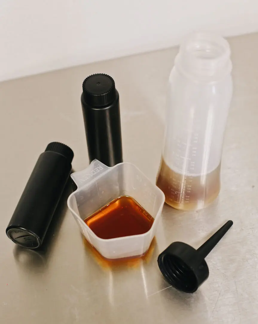 Measuring bottle and cup with amber liquid