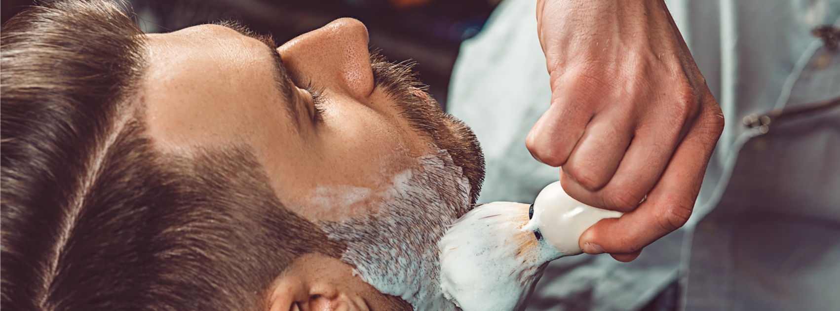 man applying shaving cream to customer