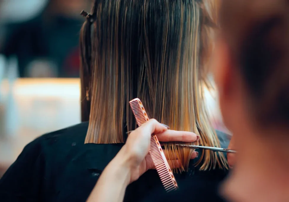Salon stylist cutting client's wet blonde hair