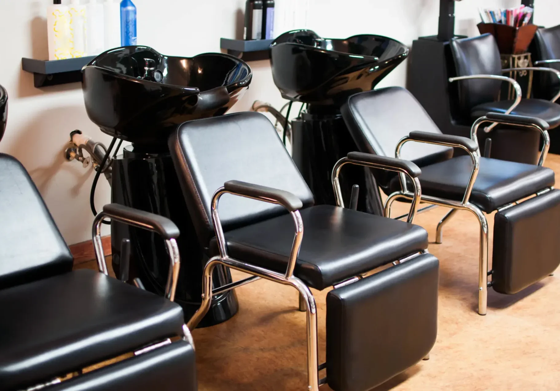 Row of black salon shampoo chairs and sinks