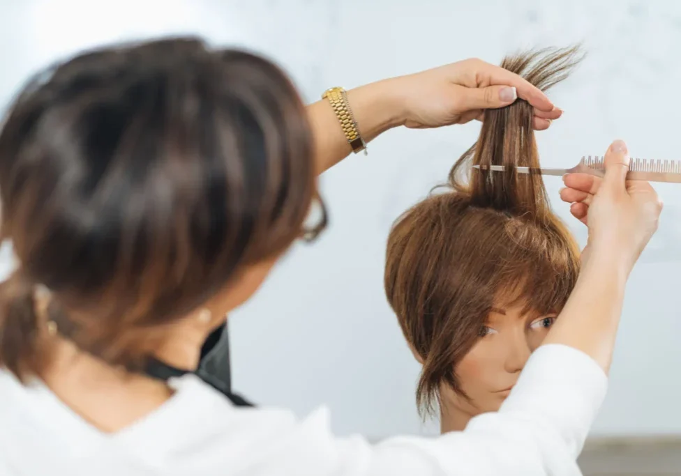 Stylist trimming layered bob on mannequin