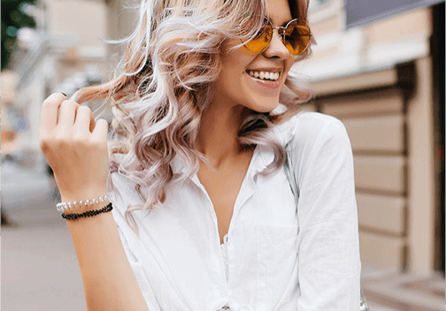 Smiling woman with sunglasses and wavy hair.