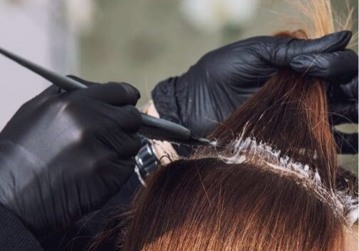 Hair dye application with black gloves.