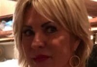 Blonde woman with hoop earrings indoors.